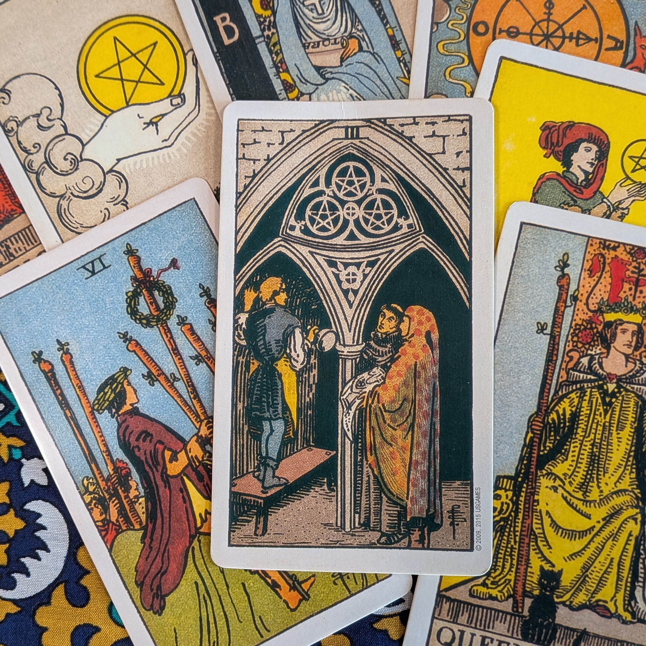 Rider–Waite–Smith tarot cards arranged around the Three of Pentacles, representing Tarot Amnesty’s mission to rehome unwanted tarot decks.